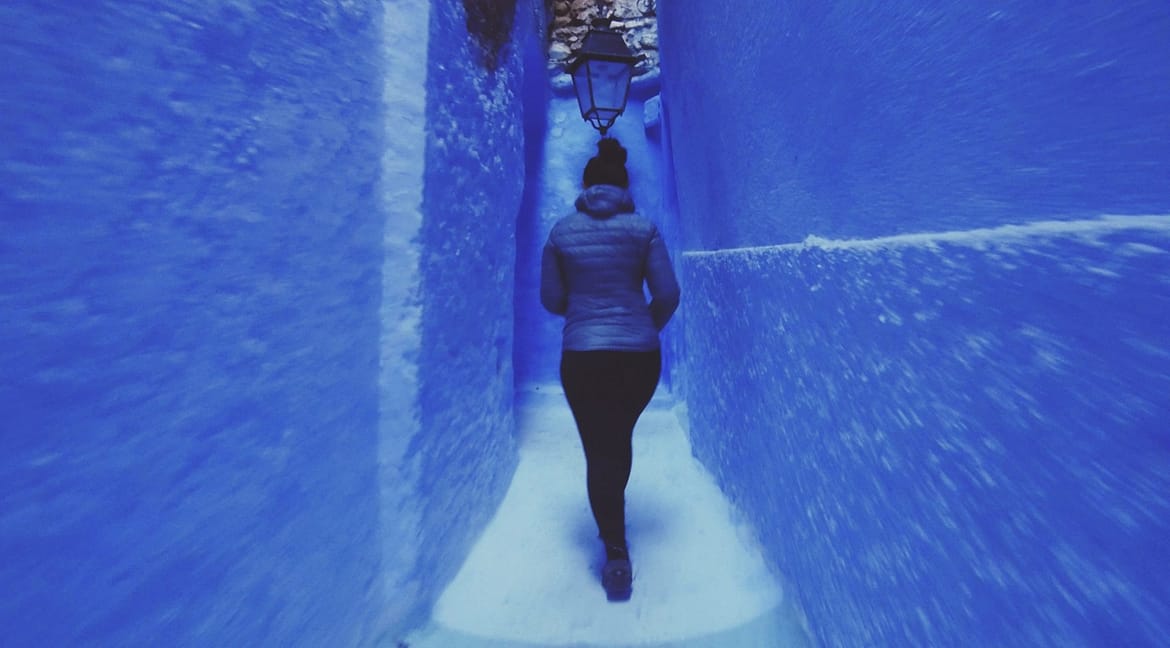 Mulher caminha nas ruelas da incrível cidade azul. Chefchauen